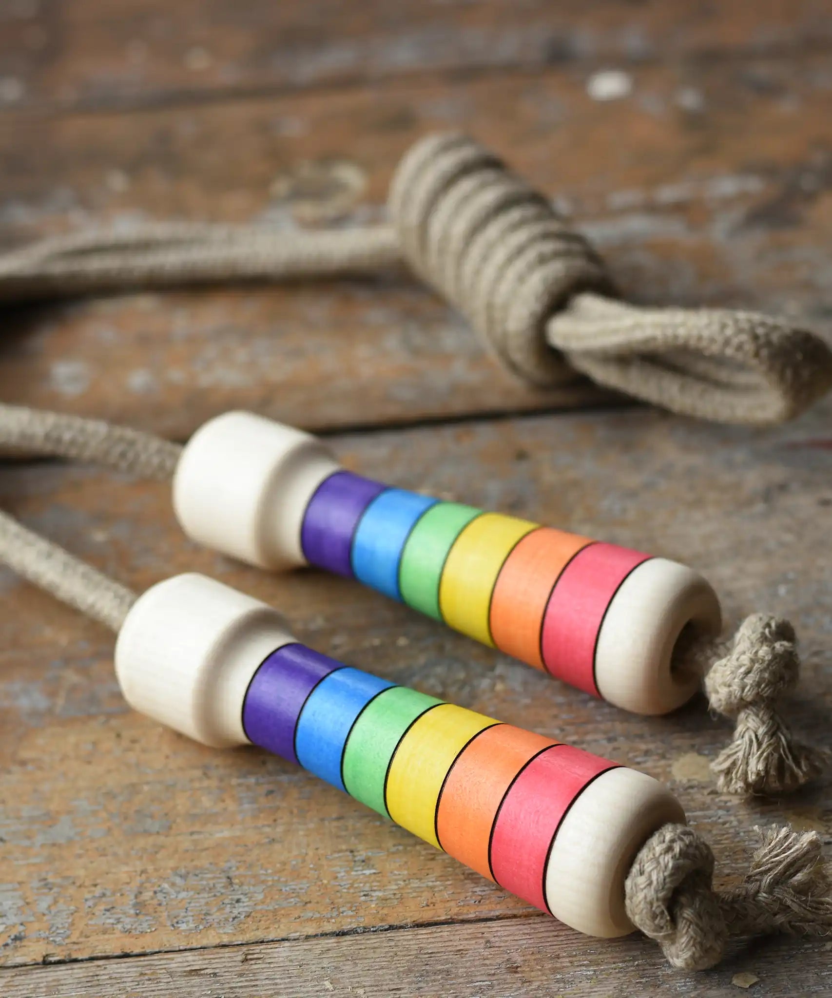 Mader Kreiselmanufaktur Children's Skipping Rope Rainbow Handles placed on a wooden surface in the Babipur playroom.