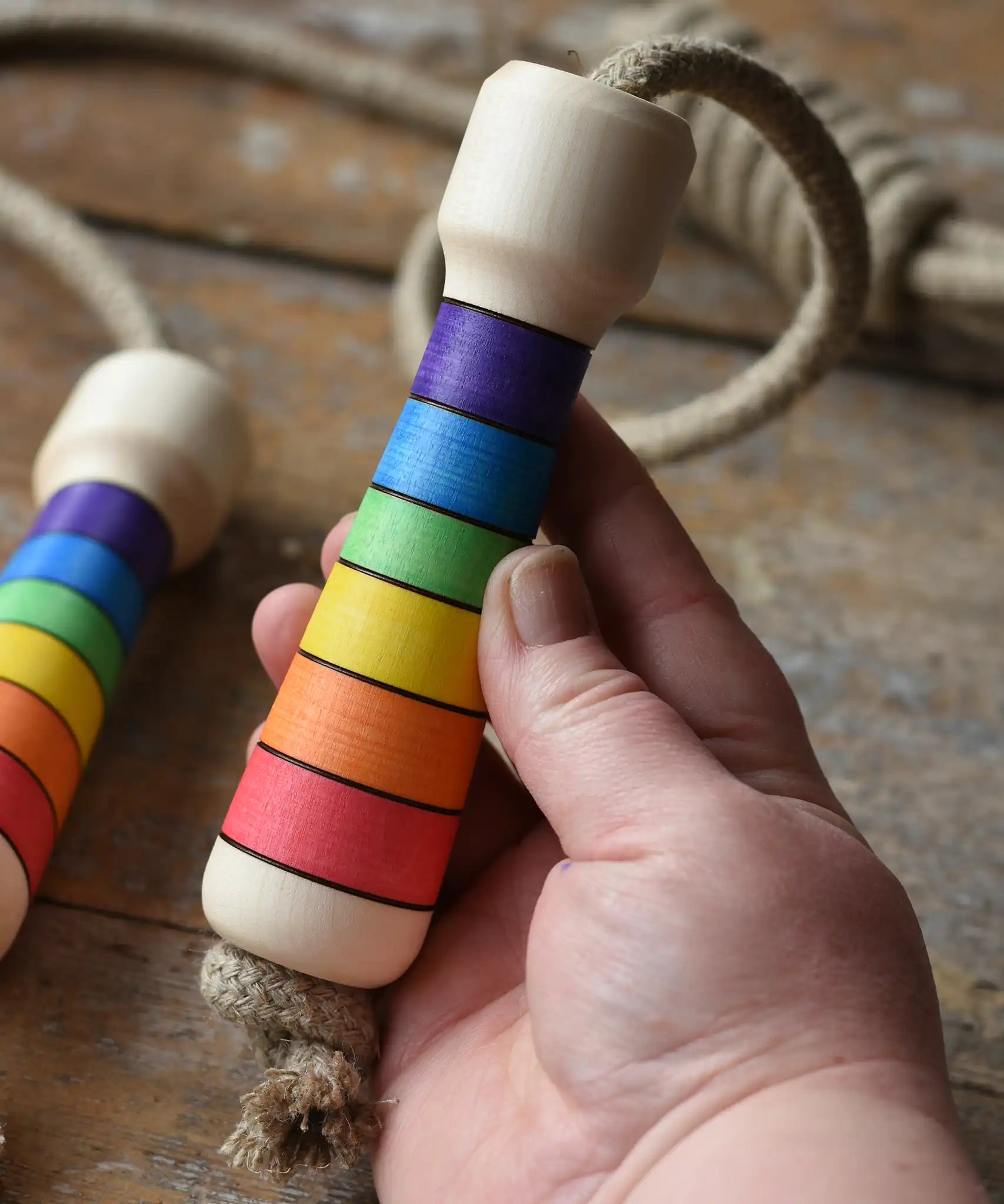 Mader Kreiselmanufaktur Children's Skipping Rope Rainbow Handles in an adult hand.
