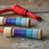 Mader Kreiselmanufaktur Children's Skipping Rope with Purple Handles placed on a wooden surface in the Babipur playroom. 