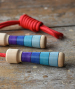 Mader Kreiselmanufaktur Children's Skipping Rope with Purple Handles placed on a wooden surface in the Babipur playroom. 