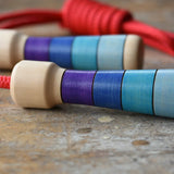 Mader Kreiselmanufaktur Children's Skipping Rope with Purple Handles placed on a wooden surface in the Babipur playroom. Close up of teh handles.