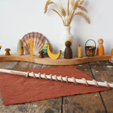 Stick from the Mader Kreiselmanufaktur Classic Whip Wooden Spinning Top placed on a wooden desk in the Babipur playroom. Decorated Grimm's celebration ring can be seen in the background. 