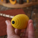 Mader Kreiselmanufaktur Classic Whip Wooden Spinning Top in yellow in an adult hand showing the base of the spinner. 