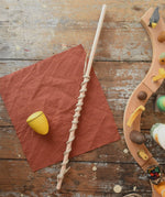 Mader Kreiselmanufaktur Classic Whip Wooden Spinning Top in yellow shown placed on a wooden desk in the Babipur playroom.
