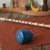 Mader Kreiselmanufaktur Classic Whip Wooden Spinning Top in blue shown placed on a wooden desk in the Babipur playroom. Close up of the wooden top.
