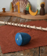 Mader Kreiselmanufaktur Classic Whip Wooden Spinning Top in blue shown placed on a wooden desk in the Babipur playroom. Close up of the wooden top.