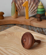 Mader classic spinning top placed on an ash spinning plate on it's side in the Babipur playroom.