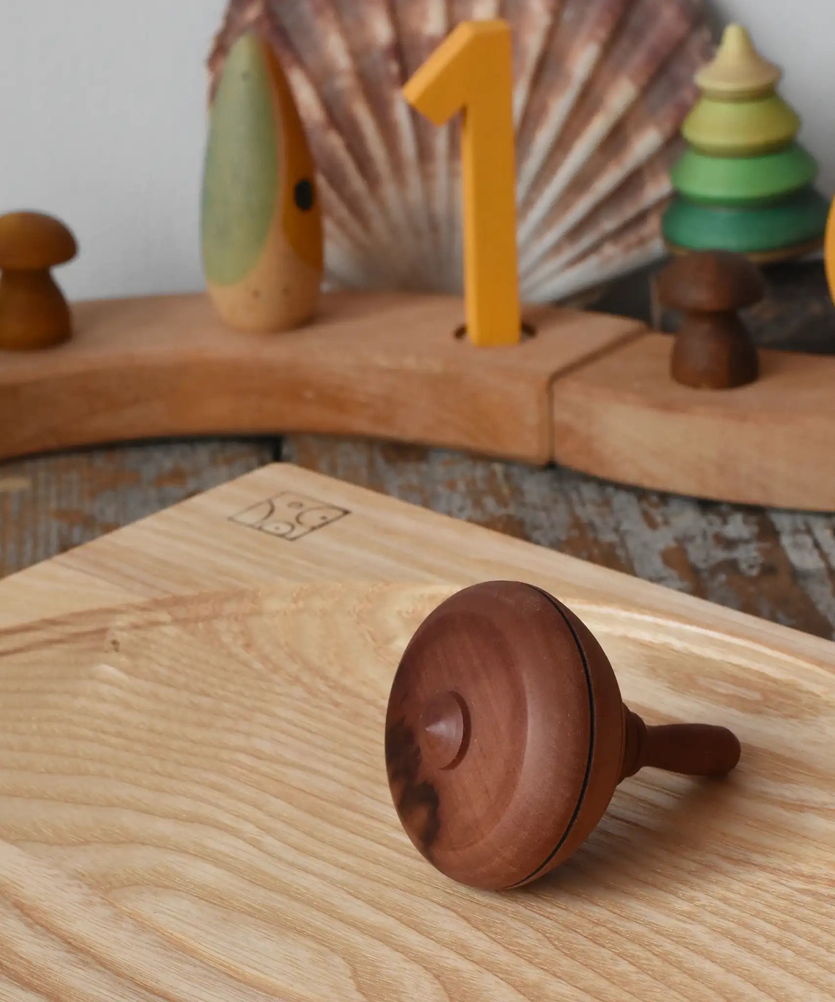Mader classic spinning top placed on an ash spinning plate on it's side in the Babipur playroom.