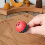 Top of the Mader Kreiselmanufaktur confetti turn-over wooden spinning top in an adult's hand in the Babipur playroom. 