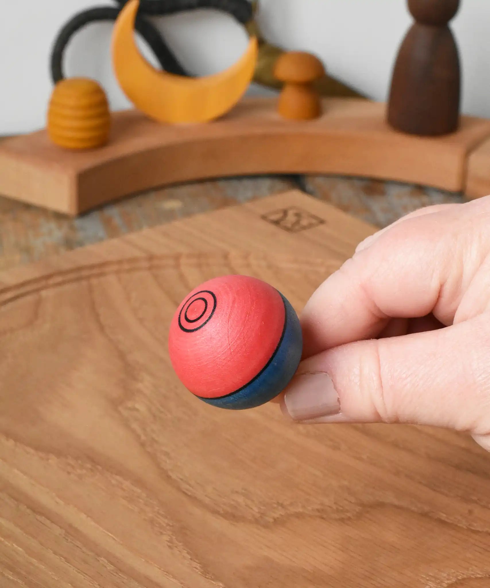 Top of the Mader Kreiselmanufaktur confetti turn-over wooden spinning top in an adult's hand in the Babipur playroom. 