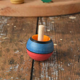 Mader Kreiselmanufaktur confetti turn-over wooden spinning top placed on a wooden desk in the Babipur playroom. 