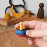 Mader Kreiselmanufaktur confetti turn-over wooden spinning top in an adult's hand in the Babipur playroom. 