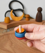 Mader Kreiselmanufaktur confetti turn-over wooden spinning top in an adult's hand in the Babipur playroom. 