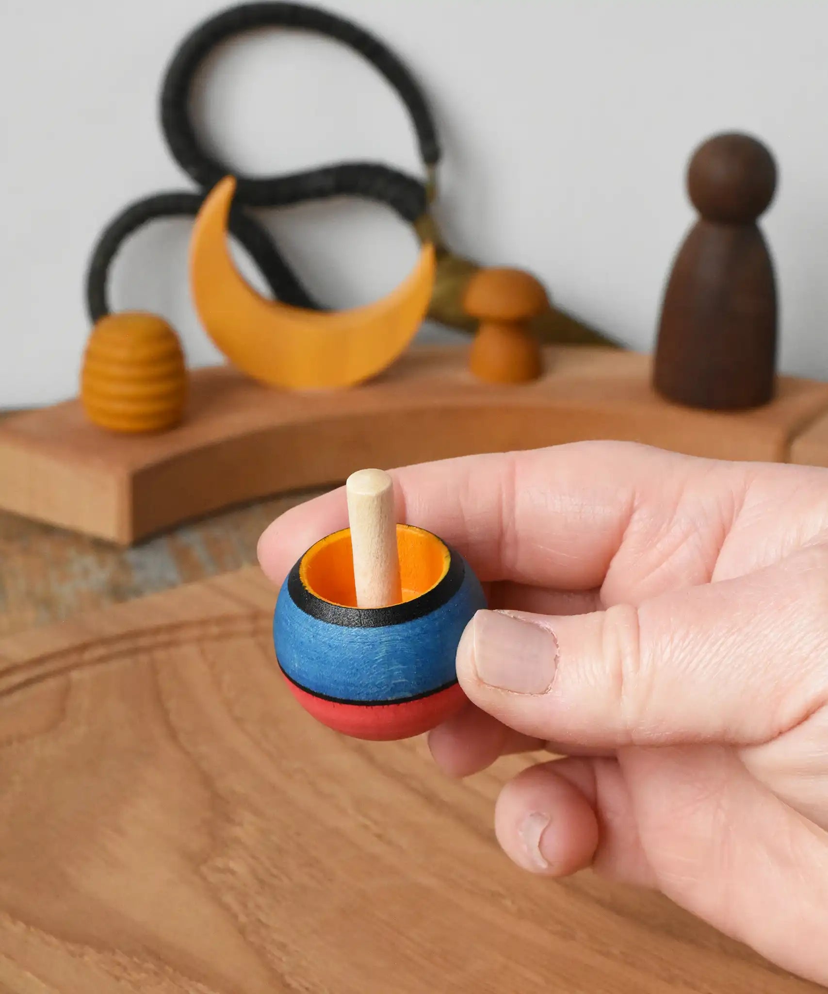 Mader Kreiselmanufaktur confetti turn-over wooden spinning top in an adult's hand in the Babipur playroom. 