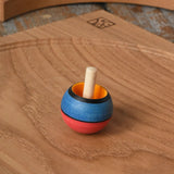 Mader Kreiselmanufaktur confetti turn-over wooden spinning top placed on an oak spinning plate in the Babipur playroom. 