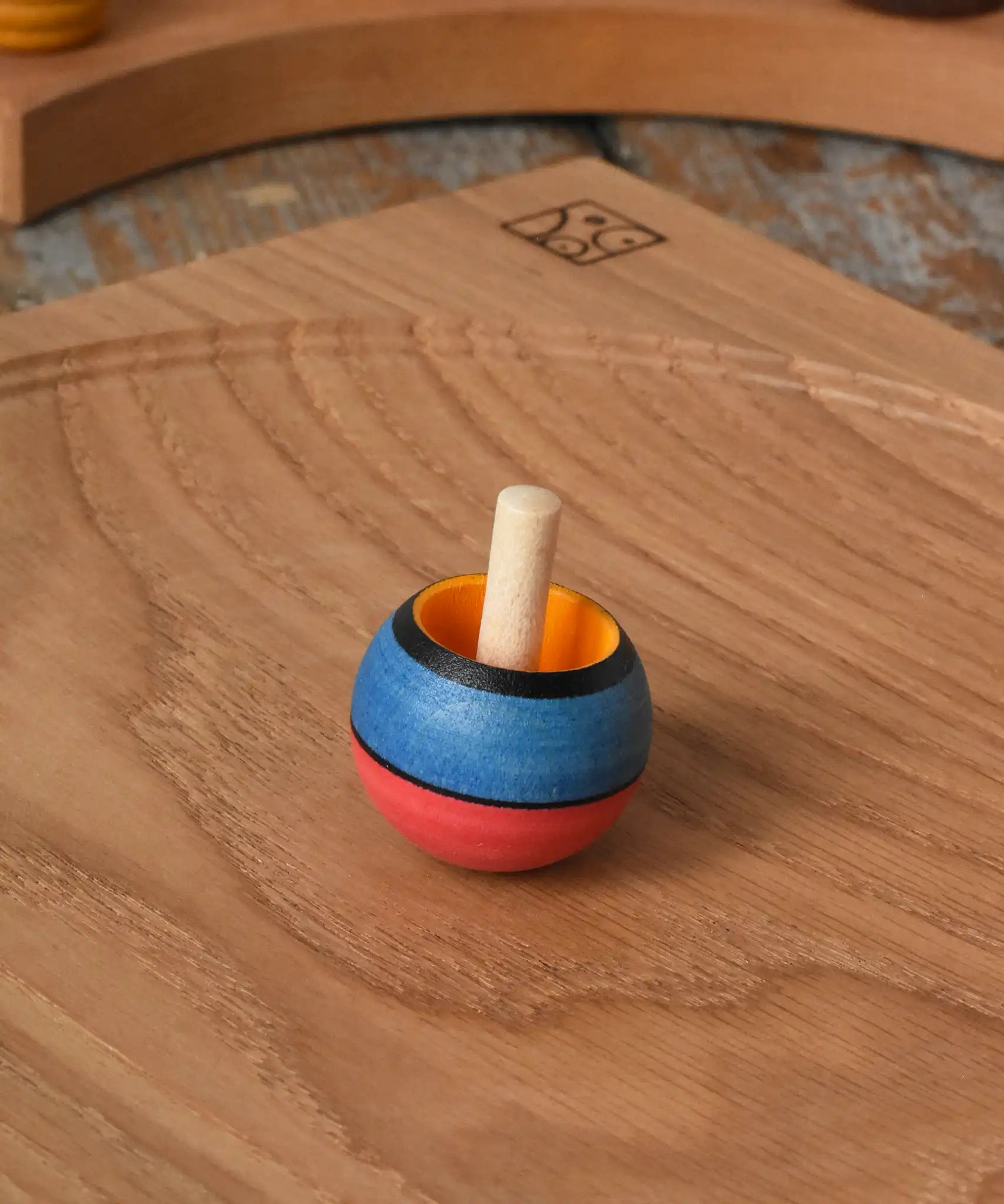 Mader Kreiselmanufaktur confetti turn-over wooden spinning top placed on an oak spinning plate in the Babipur playroom. 