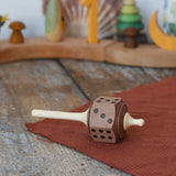 Mader Dice Spinning Top placed on a wooen desk in the Babipur playroom.