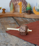 Mader Dice Spinning Top placed on a wooen desk in the Babipur playroom.