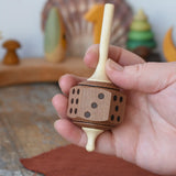Mader Dice Spinning Top in an adult's hand in the Babipur playroom.