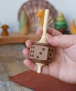Mader Dice Spinning Top in an adult's hand in the Babipur playroom.