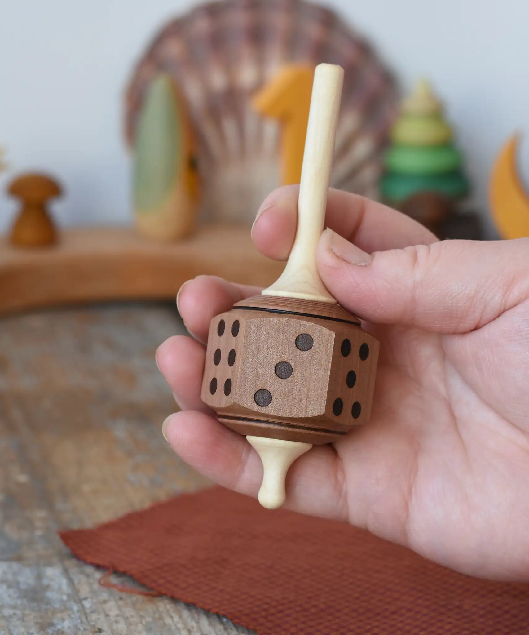 Mader Dice Spinning Top in an adult's hand in the Babipur playroom.