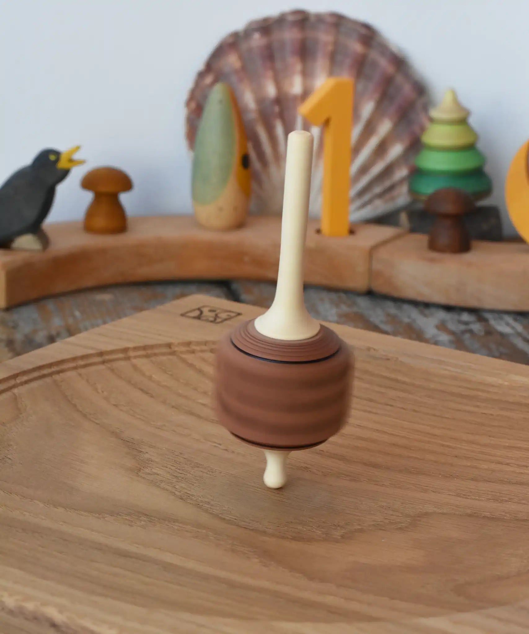 Mader Dice Spinning Top spinning, blurred in motion on an oak spinning plate in the Babipur playroom.