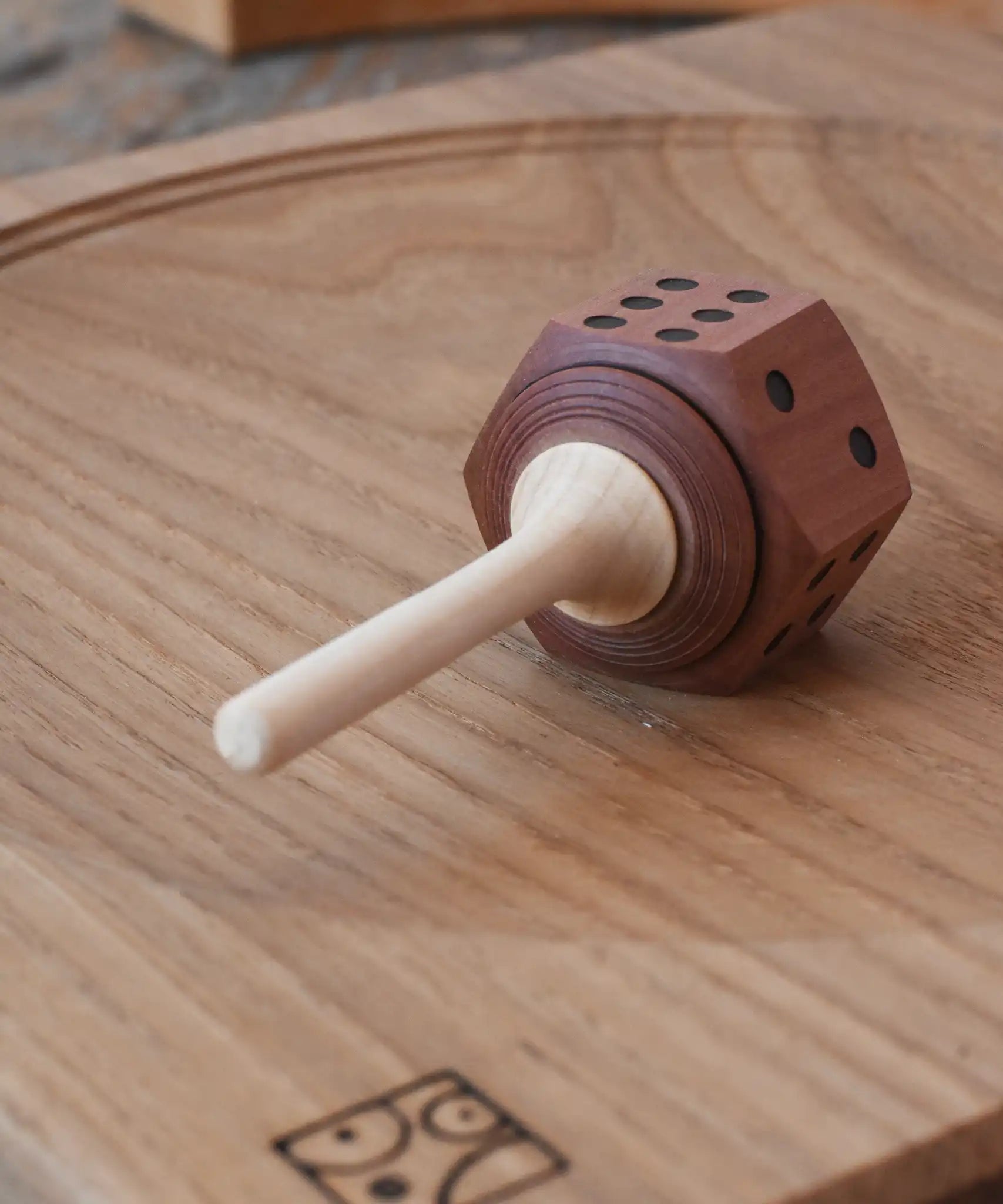Mader Dice Spinning Top placed on an oak spinning plate in the Babipur playroom.