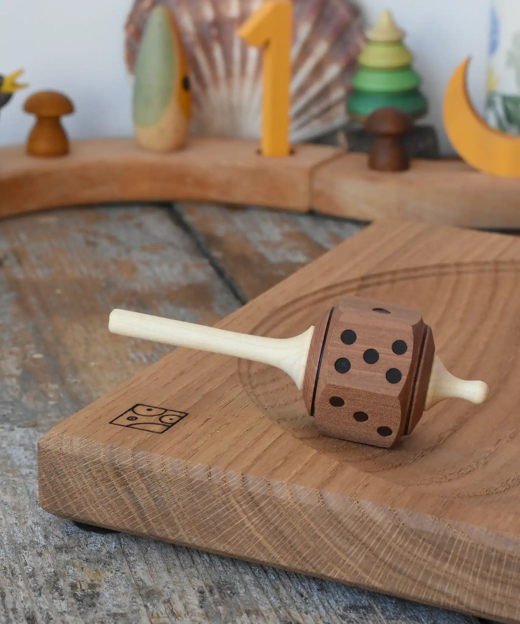 Mader Dice Spinning Top placed on an oak spinning plate in the Babipur playroom.