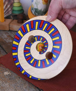 Mader Disc spinning Top Geometric placed on a wooden desk in the Babipur playroom. Adult hand holding it up 