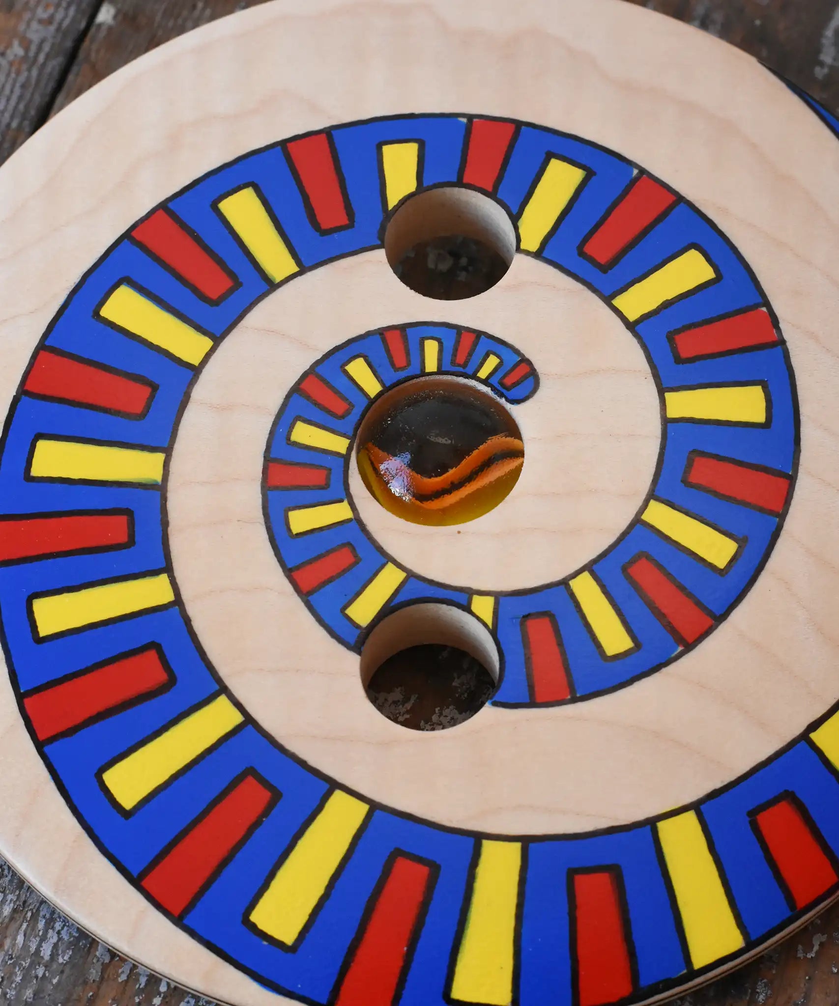 Close up of the pattern on the Mader Disc spinning Top Geometric placed on a wooden desk in the Babipur playroom.