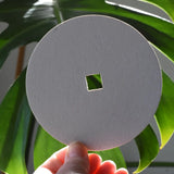 Blank Mader replacement discs for 'So And So' spinning top set in an adult's hand.
