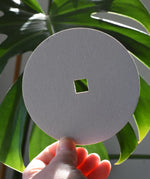 Blank Mader replacement discs for 'So And So' spinning top set in an adult's hand.