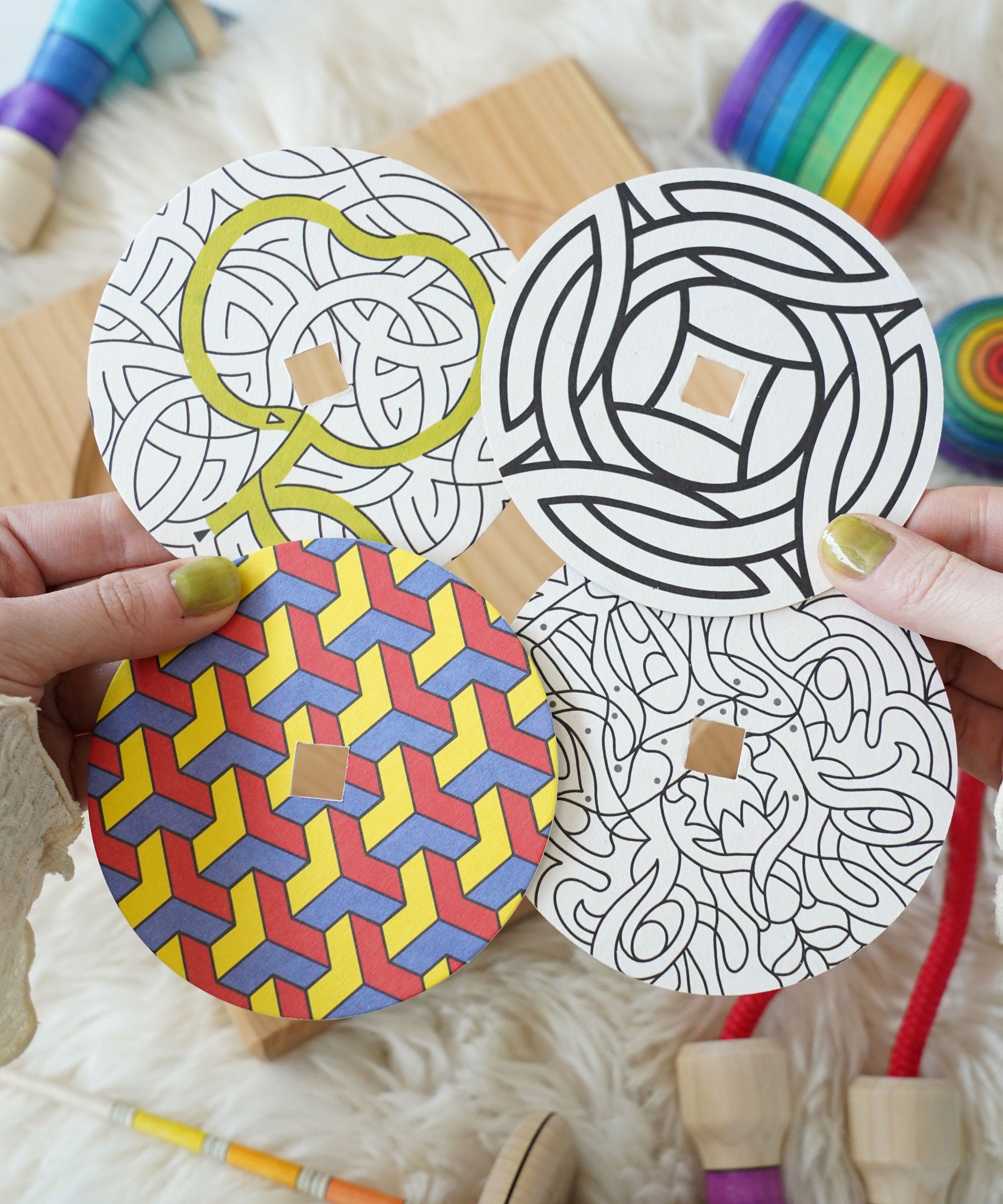 The four cardboard discs included in the Mader So and So wooden spinning top set. 