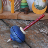 Mader Drawing spinning top in blue placed on a wooden desk in the Babipur playroom.