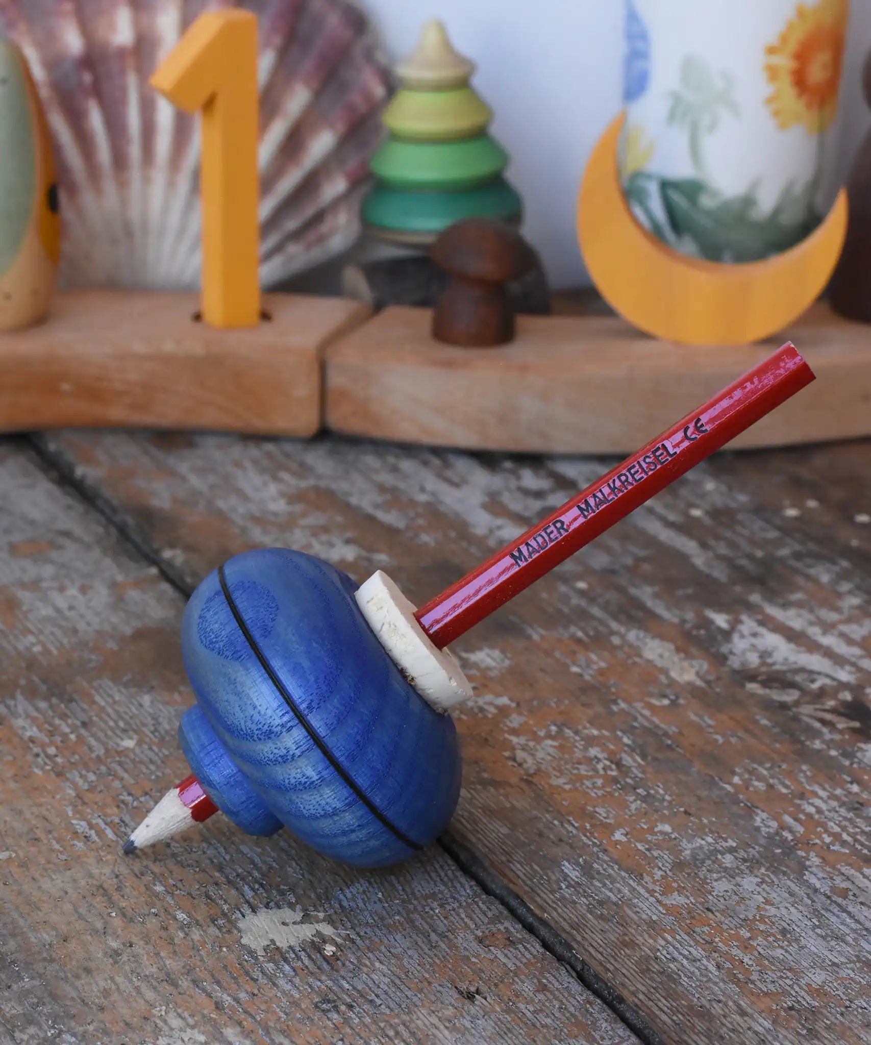 Mader Drawing spinning top in blue placed on a wooden desk in the Babipur playroom.