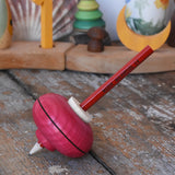 Mader Drawing spinning top in red placed on a wooden desk in the Babipur playroom.