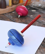 Mader Drawing spinning top in blue placed on paper in the Babipur playroom.