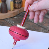 Mader Drawing spinning top in red placed on paper which has pencil marks on in the Babipur playroom.