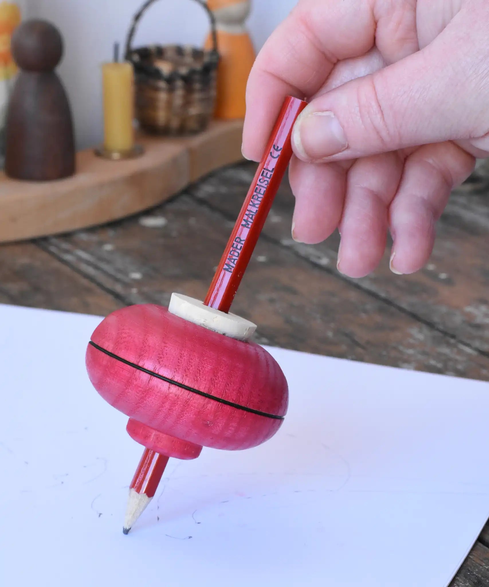 Mader Drawing spinning top in red placed on paper which has pencil marks on in the Babipur playroom.
