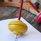 Mader Drawing spinning top placed on paper which has pencil marks on in the Babipur playroom.
