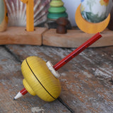 Mader Drawing spinning top in yellow placed on a wooden desk in the Babipur playroom.