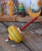 Mader Drawing spinning top in yellow placed on a wooden desk in the Babipur playroom.