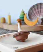 Mader duet spinning top wooden toy placed on a medium maple spinning plate.
