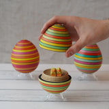Mader Summer stripe egg with two little Bumbu chicks placed inside, an adult hand can be seen lifting the lid off.