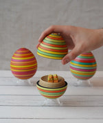 Mader Summer stripe egg with two little Bumbu chicks placed inside, an adult hand can be seen lifting the lid off.