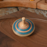 Blue Mader Kreiselmanufaktur fado maple wooden finger spinning top placed on a walnut spinning plate in the Babipur playroom.