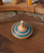Blue Mader Kreiselmanufaktur fado maple wooden finger spinning top placed on a walnut spinning plate in the Babipur playroom.