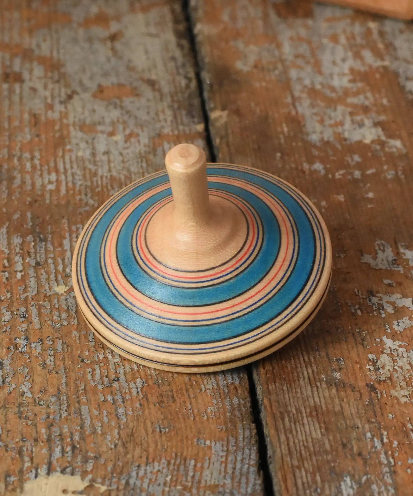 Blue Mader Kreiselmanufaktur fado maple wooden finger spinning top placed on a wooden surface in the Babipur playroom.