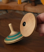 Bottom of the Mader Kreiselmanufaktur fado maple wooden finger spinning top in an adult's hand.