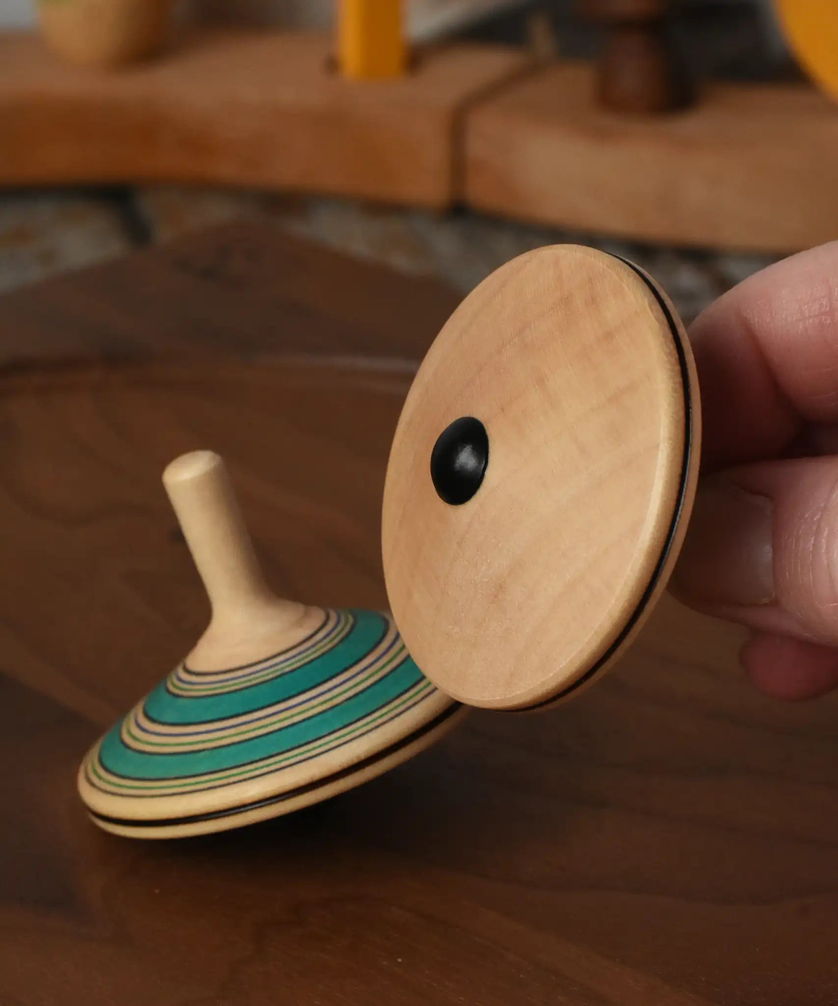 Bottom of the Mader Kreiselmanufaktur fado maple wooden finger spinning top in an adult's hand.